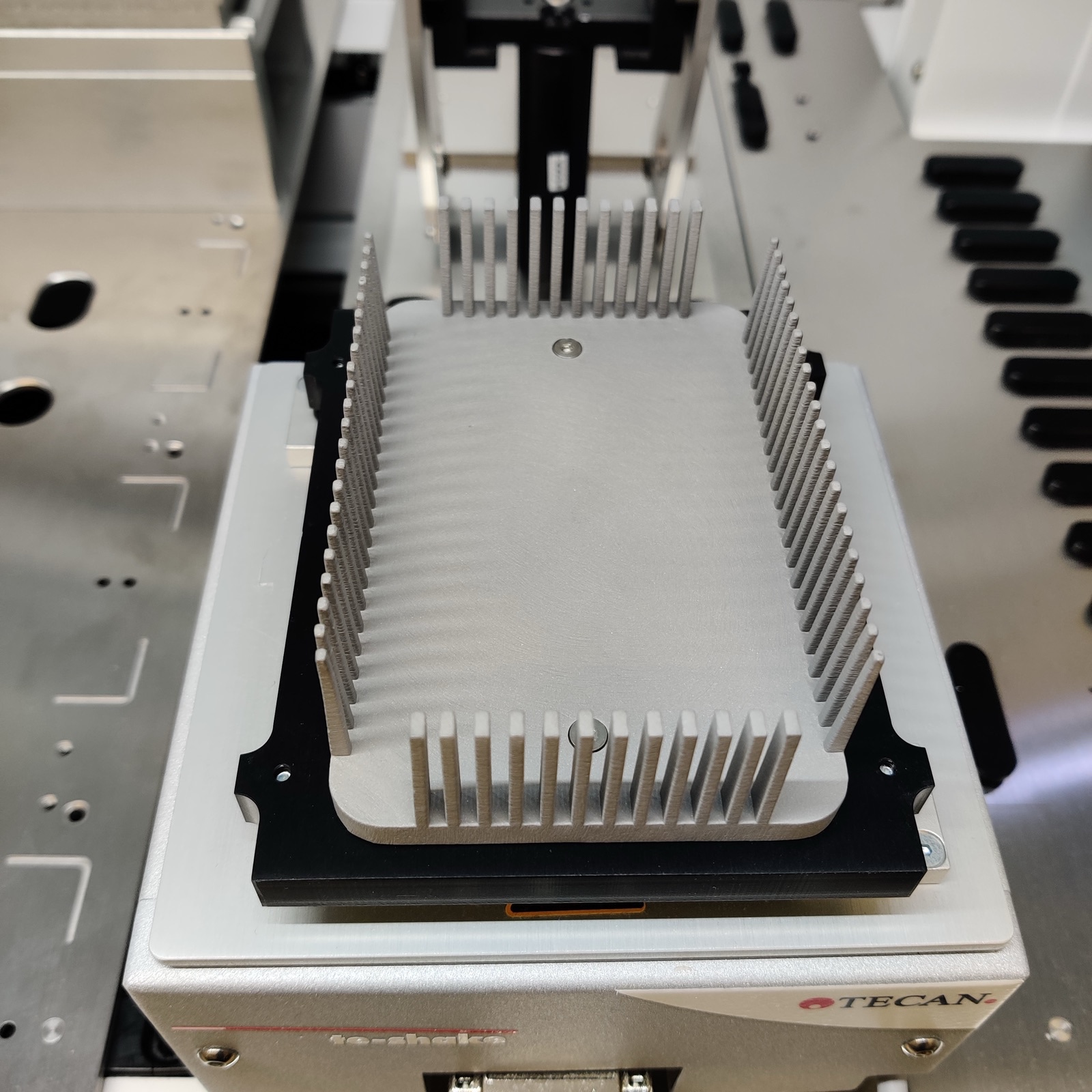 A finned brushed-aluminum plate holder seated in a Tecan Te-Shake module on a liquid handler deck